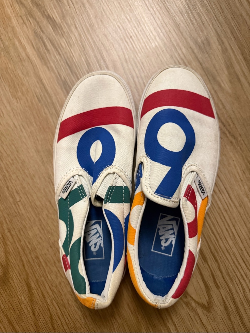 Vans Kids Slip-On Sneakers in White with Red, Blue & Green Accents